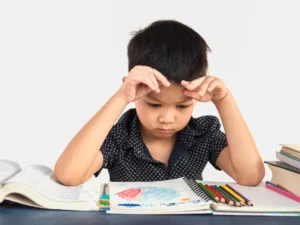 A young boy focusing intently on his notebook and colored pencils, representing a child learning Spanish in Spain.