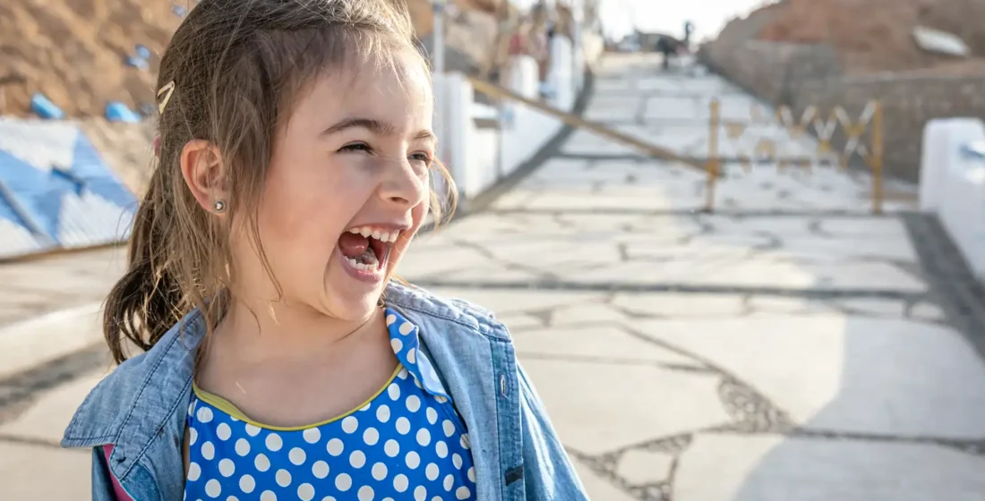 A young girl laughing and looking with excitement toward something in the distance, showing the confidence and joy of learning in a new environment.