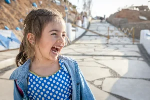 A young girl laughing and looking with excitement toward something in the distance, showing the confidence and joy of learning in a new environment.