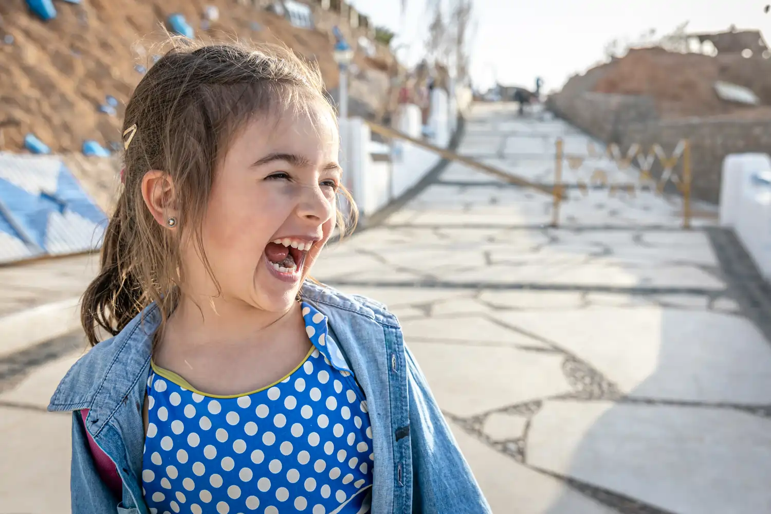 A young girl laughing and looking with excitement toward something in the distance, showing the confidence and joy of learning in a new environment.