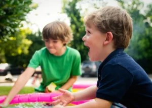 A joyful young boy laughing while playing in a colorful outdoor setting with a friend, illustrating a gentle entry point for settling in a new country.