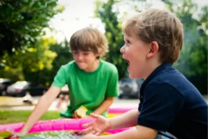 A joyful young boy laughing while playing in a colorful outdoor setting with a friend, illustrating a gentle entry point for settling in a new country.