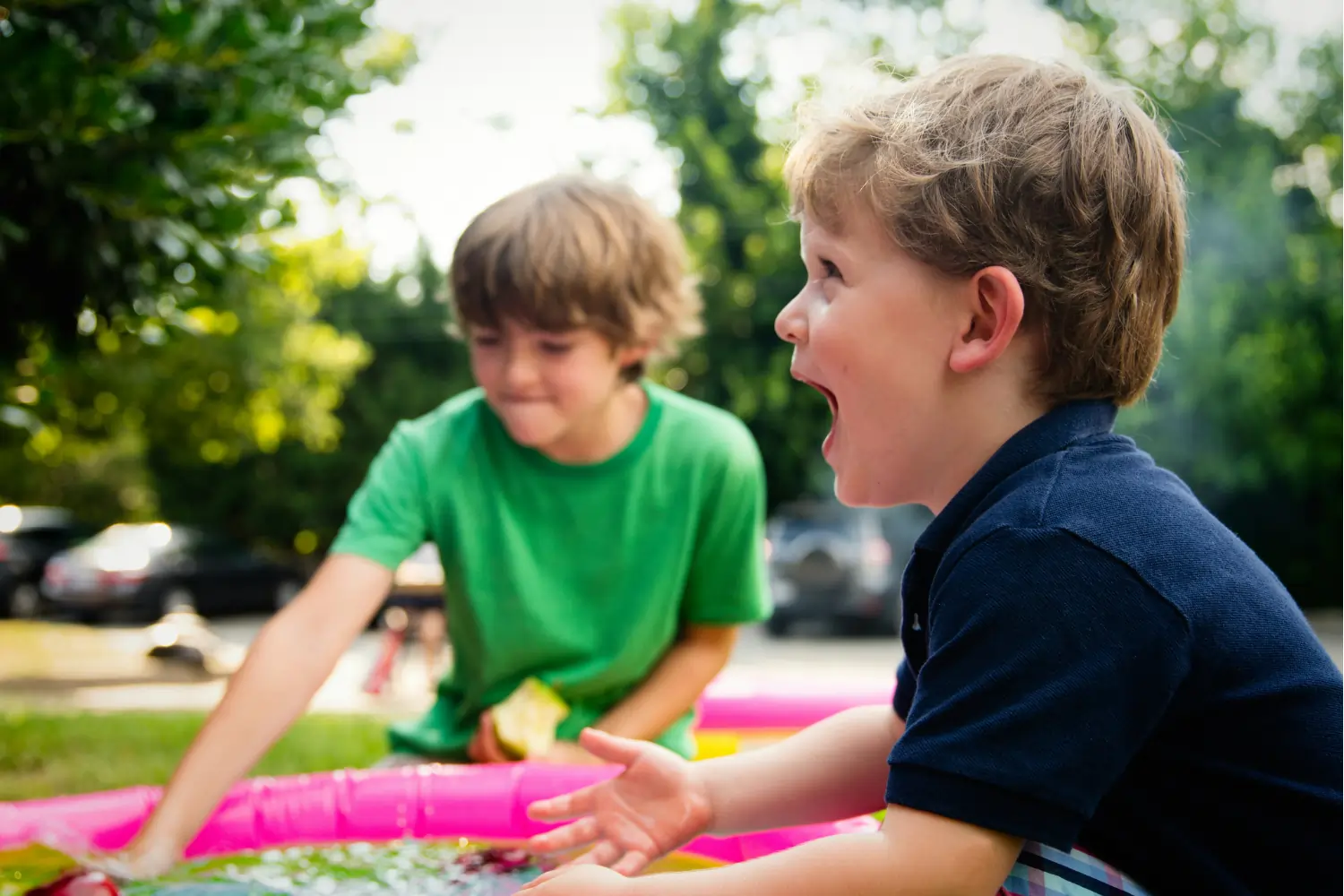 A joyful young boy laughing while playing in a colorful outdoor setting with a friend, illustrating a gentle entry point for settling in a new country.